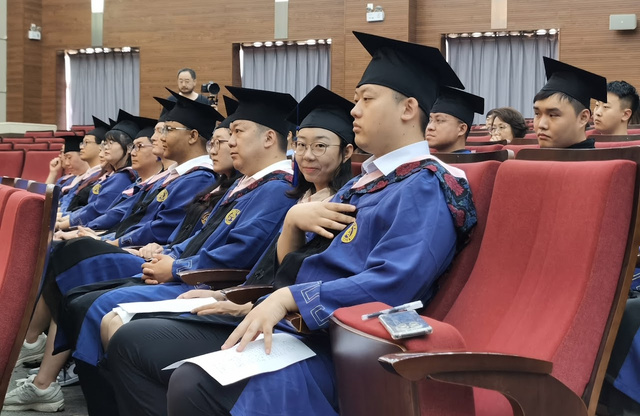 A candid photo of some of the MSHROD graduates seated in an auditorium looking towards a stage. One graduate smiles at the camera. 