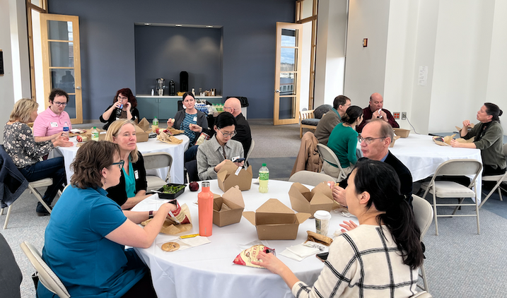 a group of people sitting around several tables eating food