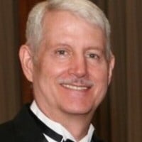 D. Robert Okopny in a tuxedo and bow tie smiling at the camera.