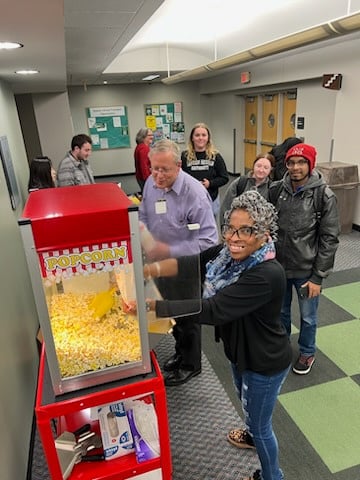 a group of EMU students and staff members stand around a popcorn machine