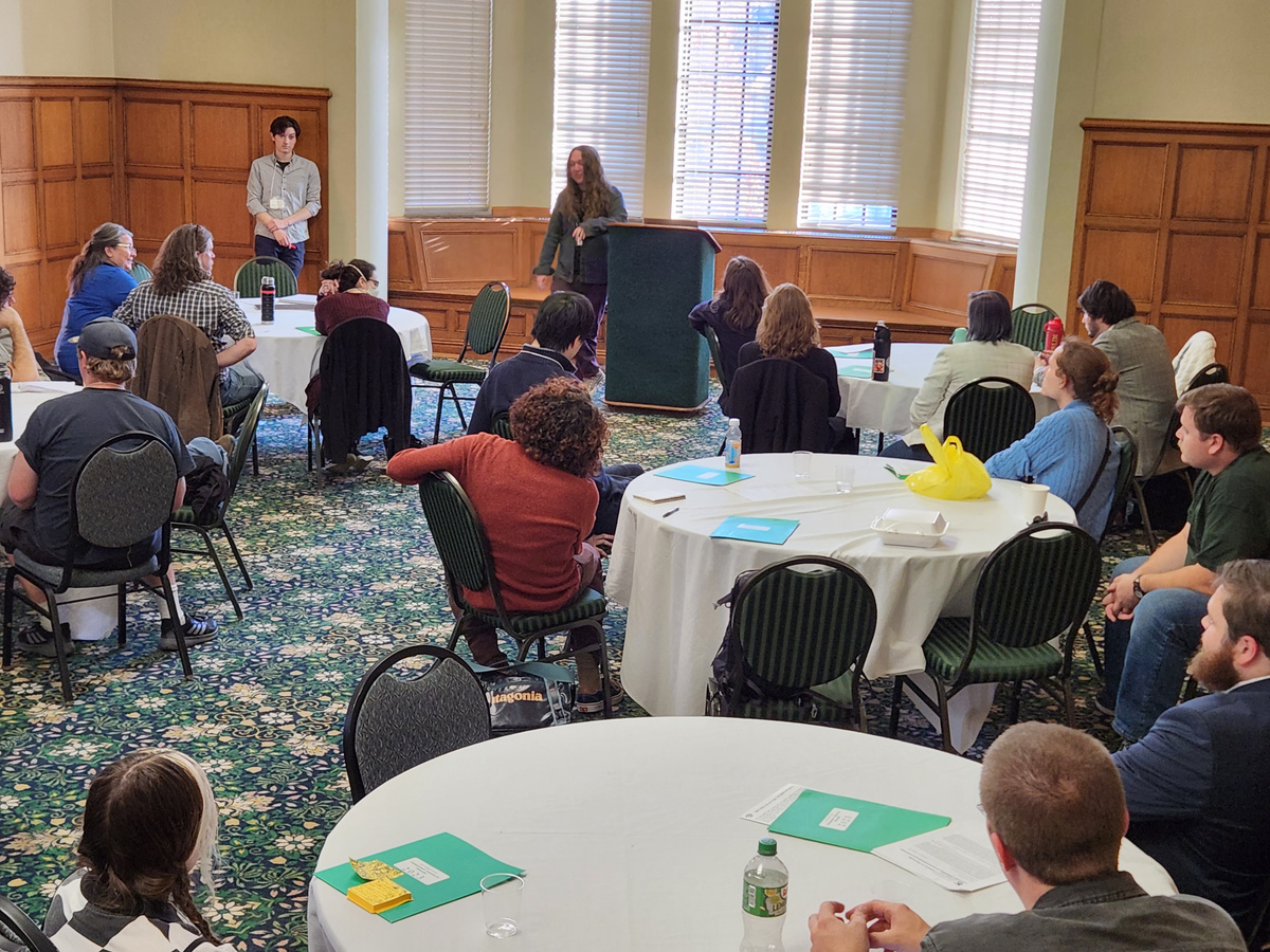 Attendees of UCiP sit at round tables listening to a presentation