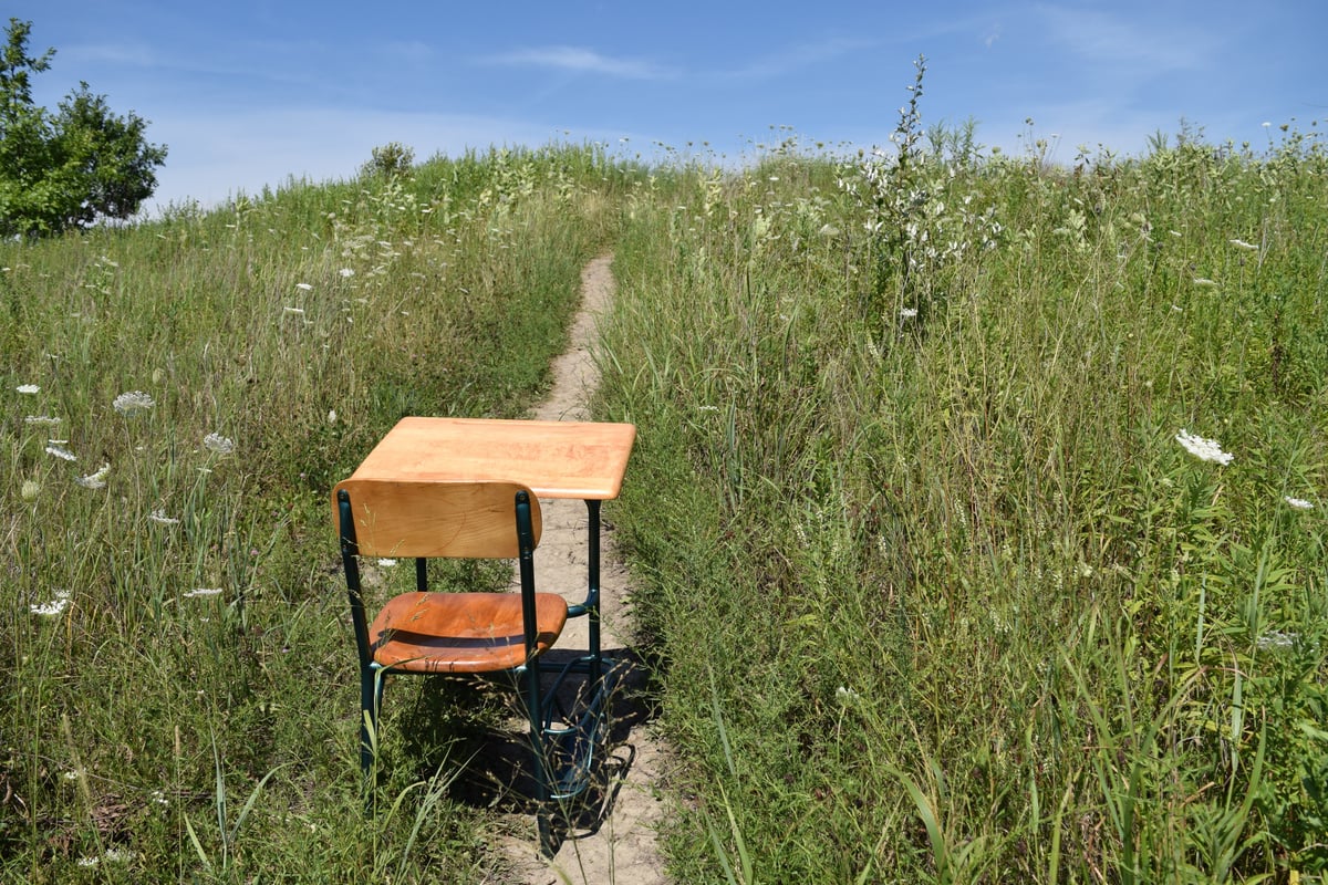 a photograph of a school desk in the middle of a field