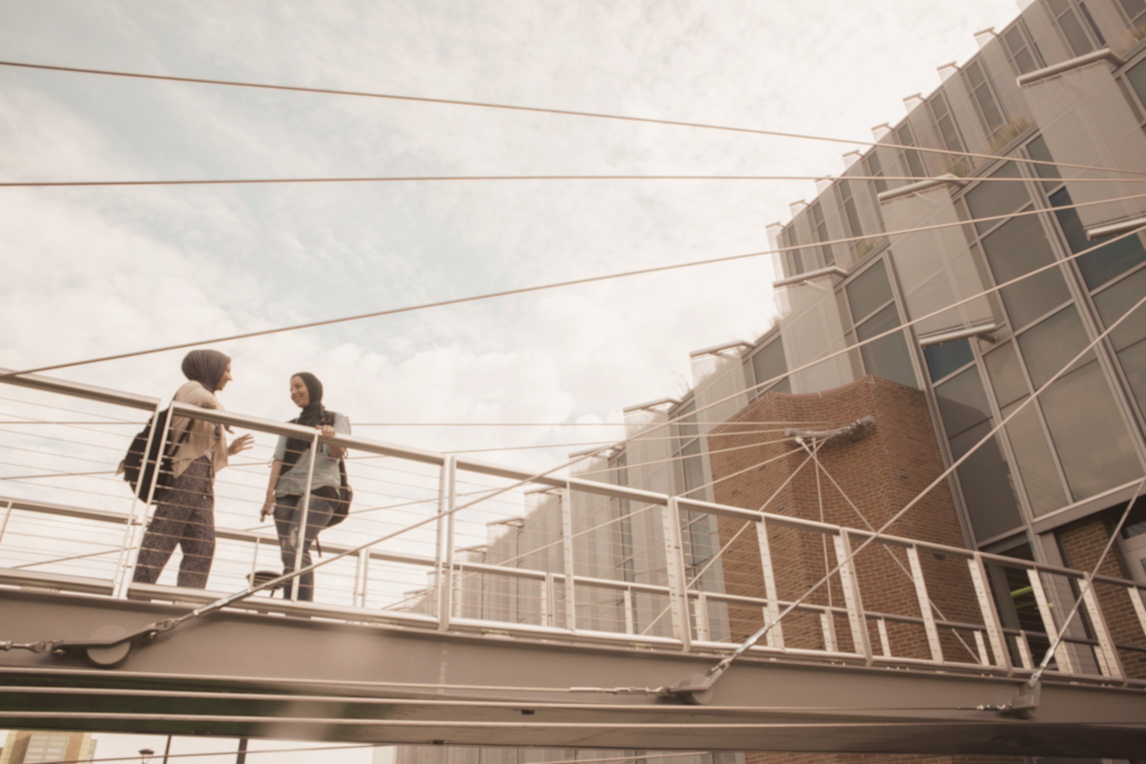 two people standing on a bridge in front of a building