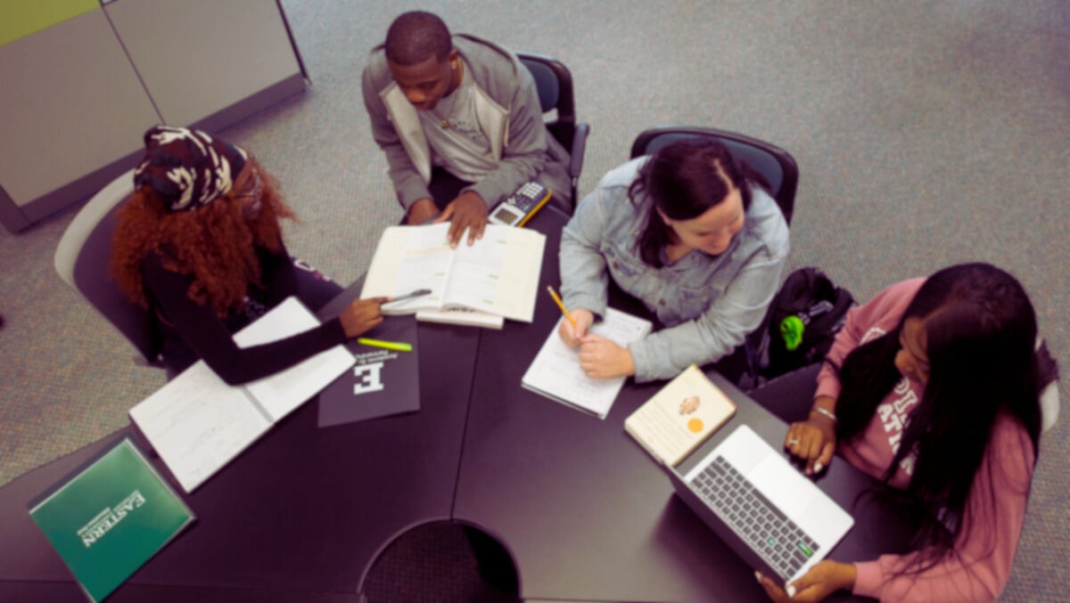 a group of people sitting around a table with laptops