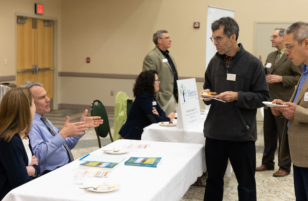 a group of people standing around a table at a conference