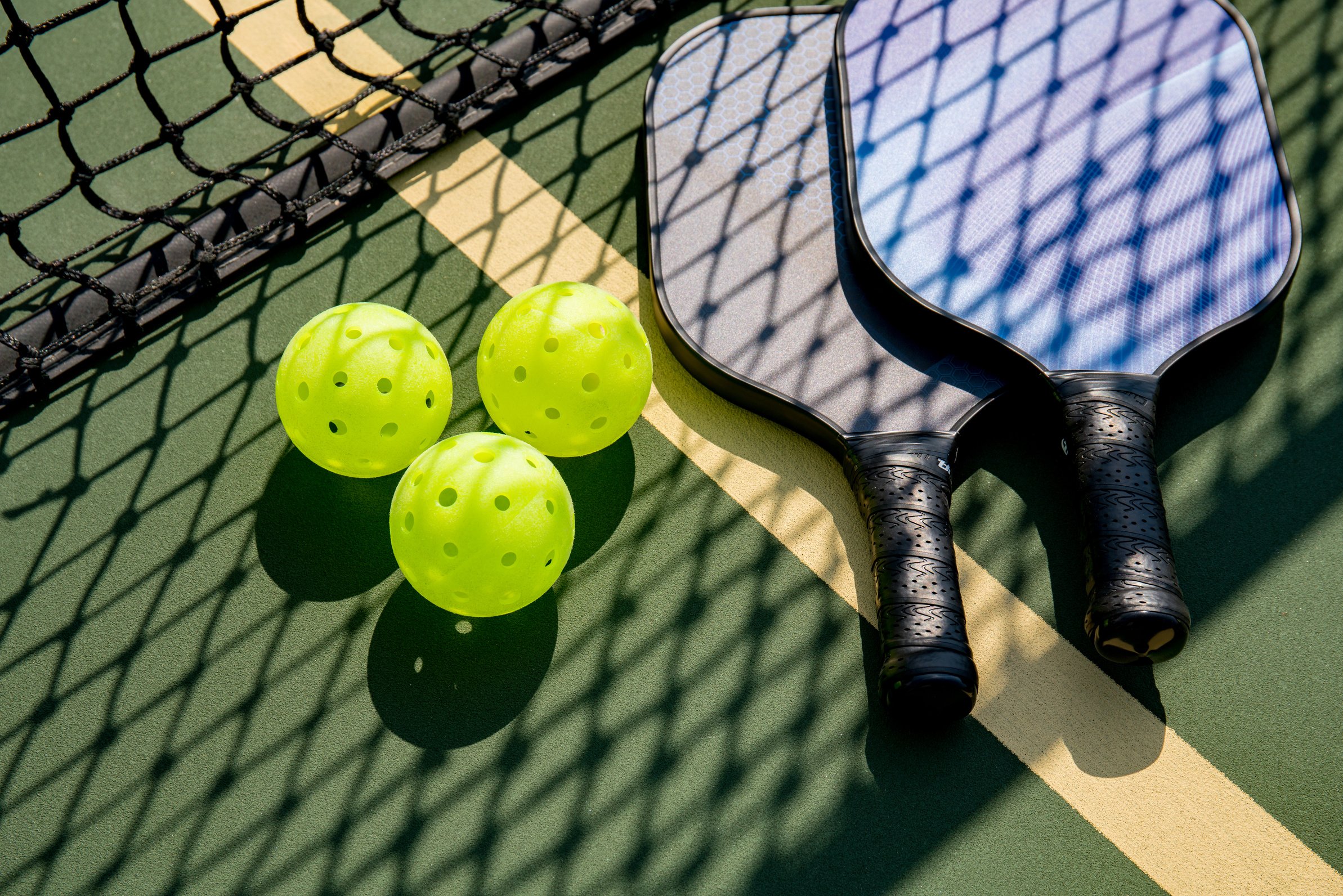 Pickleball paddle and balls on a tennis court