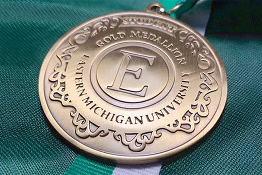 a medal with the letter e on it sitting on top of a green and white ribbon