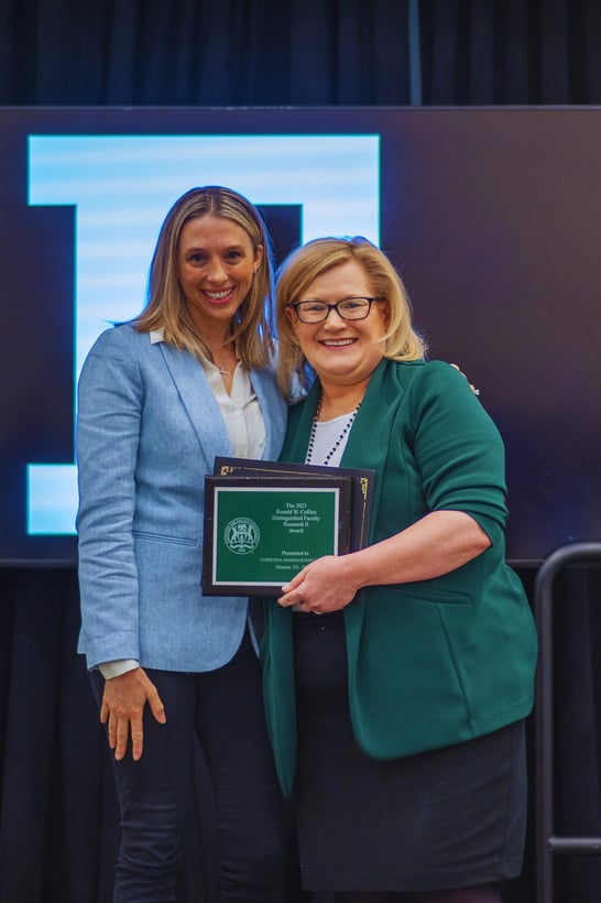 two people standing next to each other holding an award