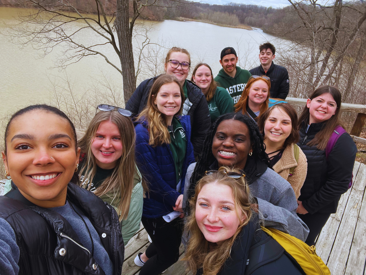 a group of students taking a selfie in front of a body of water