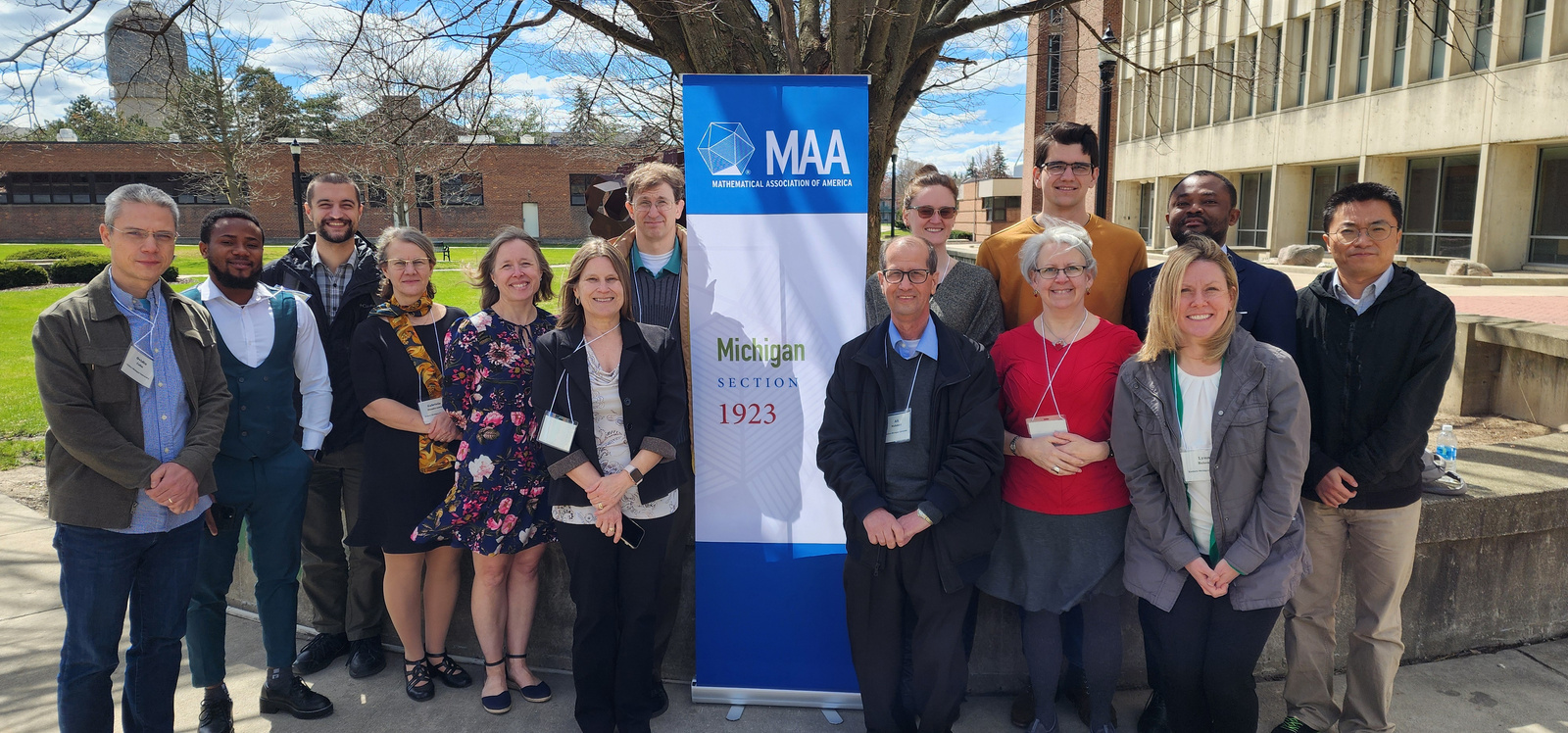 a group of people pose for a photo outside standing in front of a banner for MAA