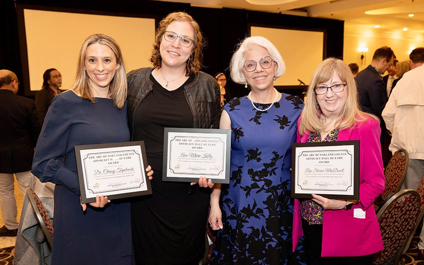 four people are holding awards at an event