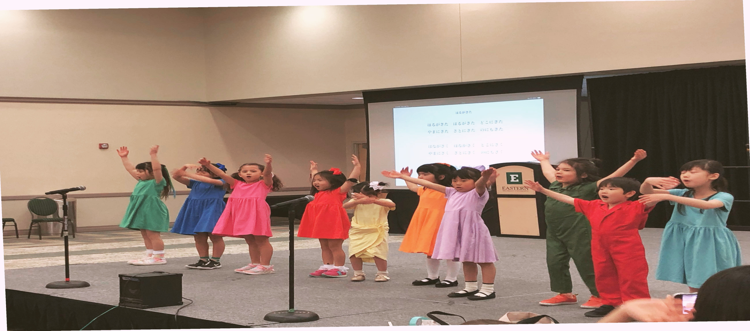 a group of children standing on stage with their hands in the air