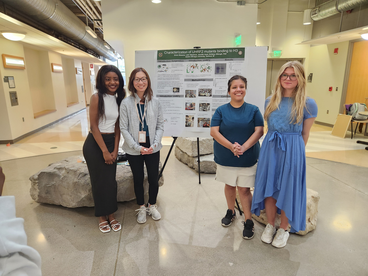 four young students standing next to each other in front of an informational poster