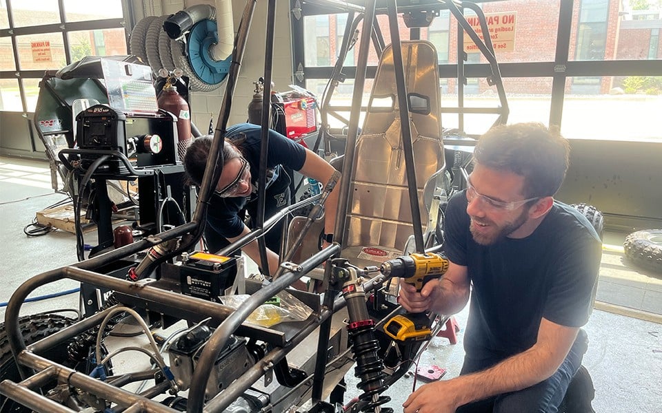 two people working on an engine in a garage