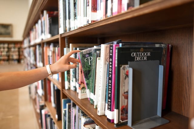 A hand reaching for a book at a library.