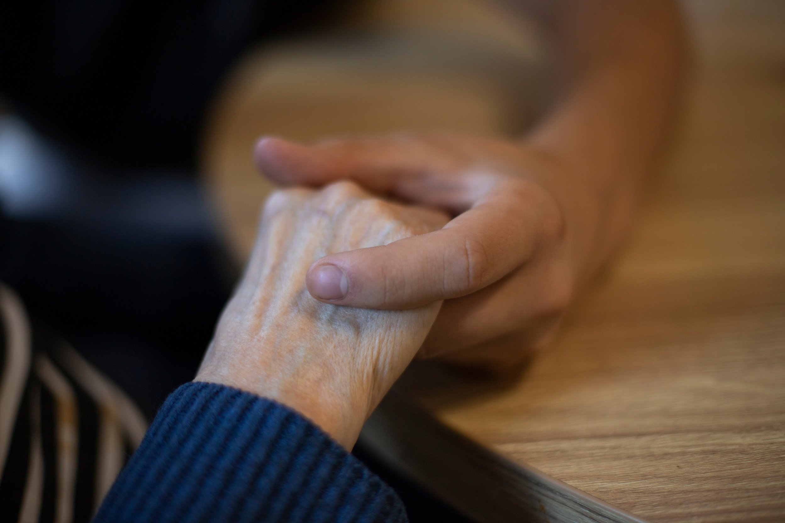 close-up of a young man's hand holding an elderly person's hand. Symbol of compassion and intergenerational mutual aid