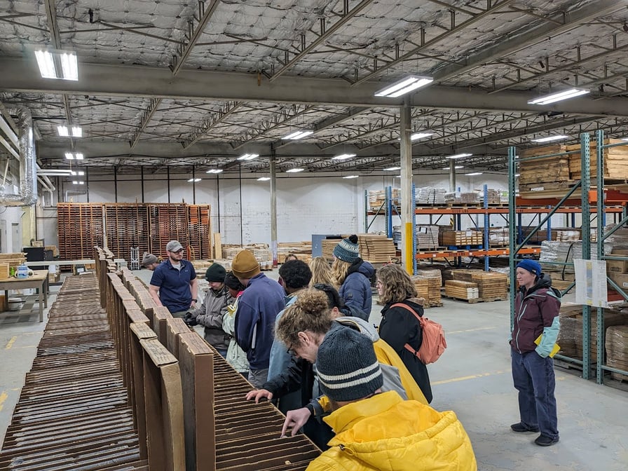 a group of people in a warehouse looking at wood