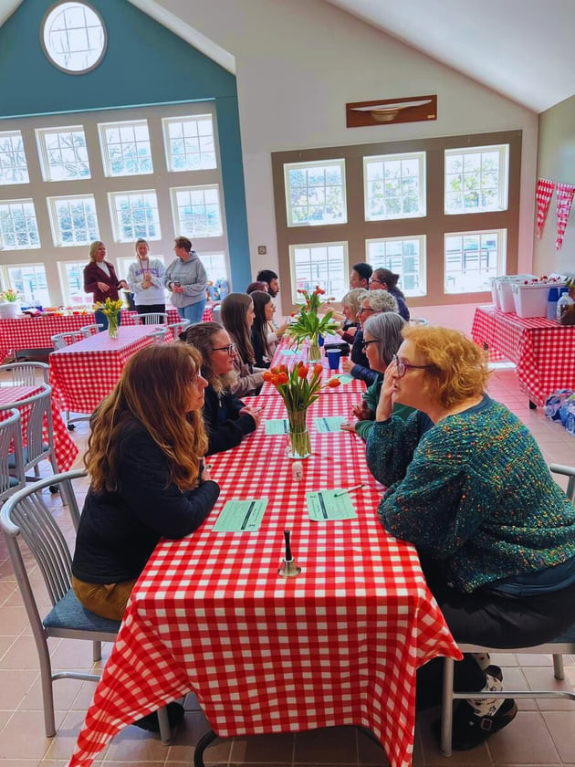 a group of people sitting at a table with red and white checkered tablecloths