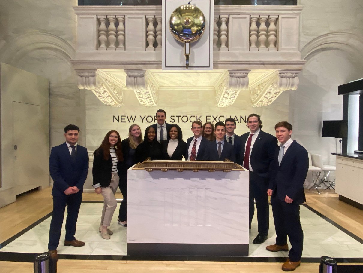 A group photo of the EMU chapter posing inside the marble and gilded NYC stock exchange building 