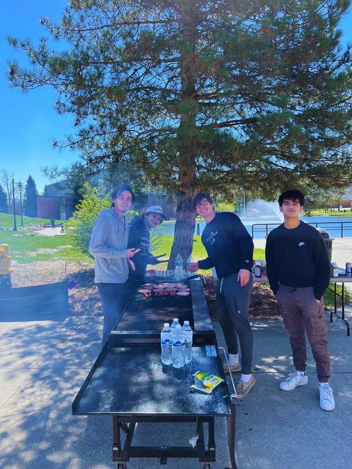 a group of people standing around an outdoor grill