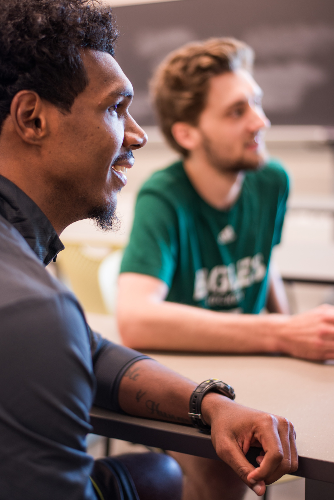 two people sitting at a table in front of a blackboard