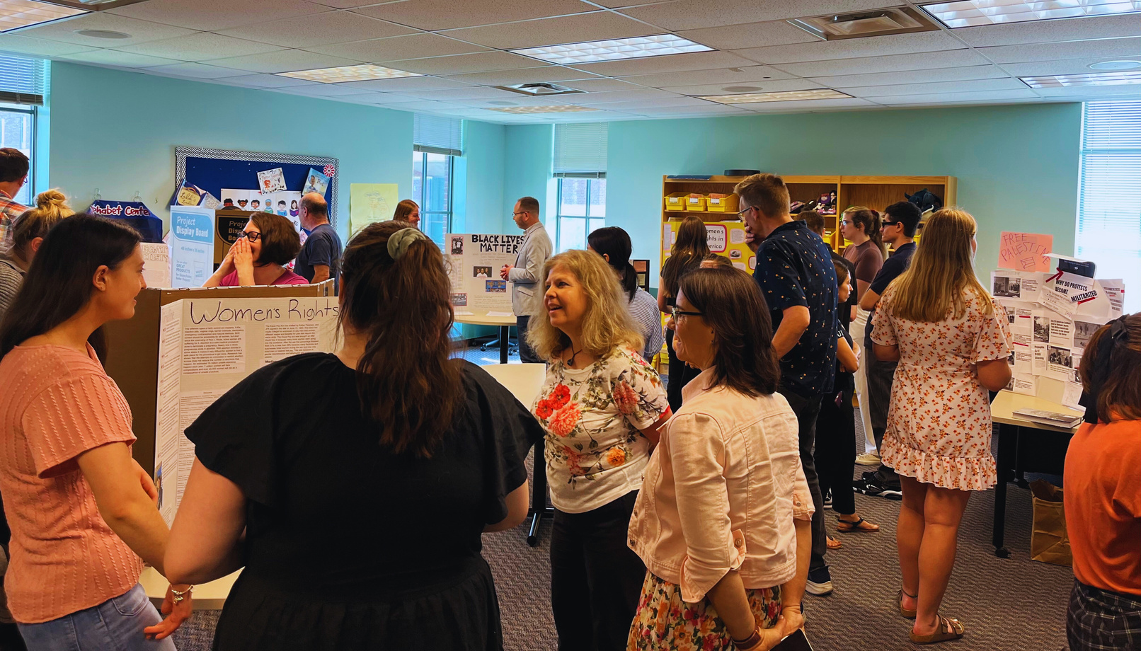 a group of people standing around a table with posters on it