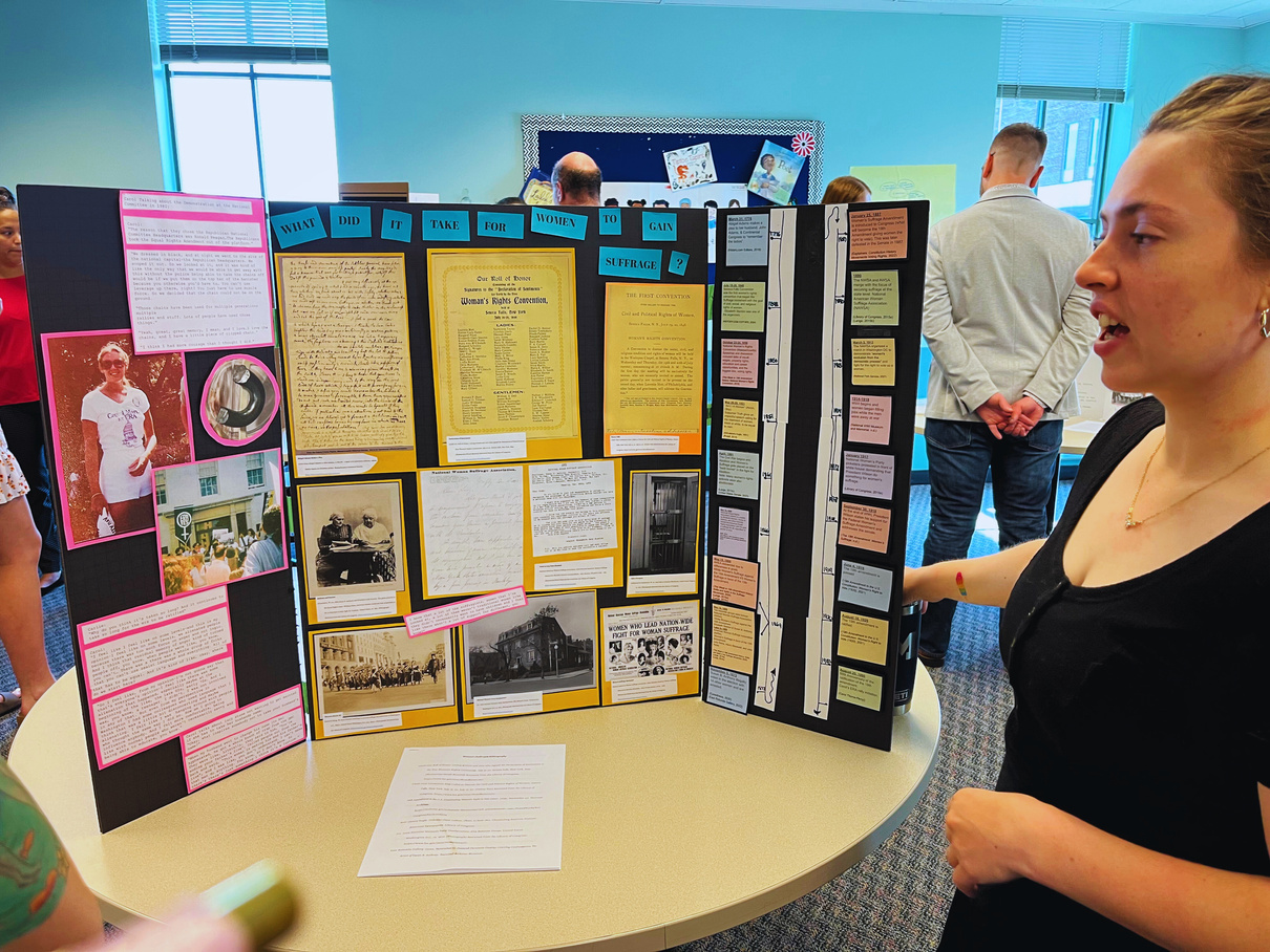 a person standing next to a table with a poster on it