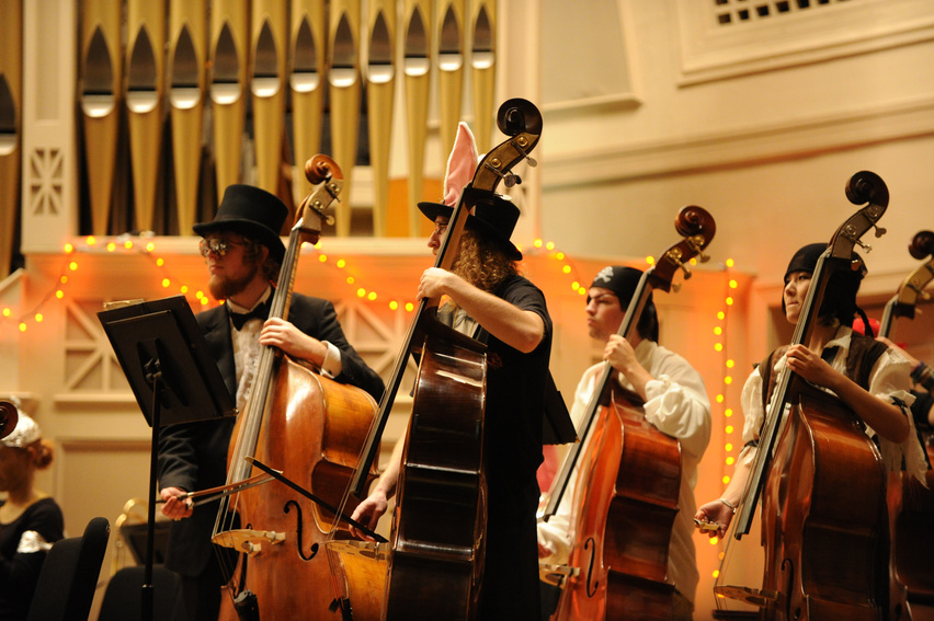 a group of people in top hats and bow ties playing cellos