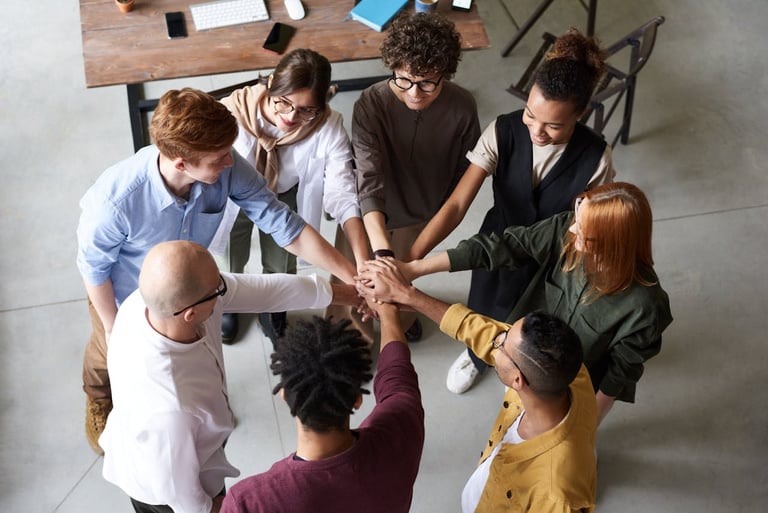 A circle of people put their hands in the center of the circle together