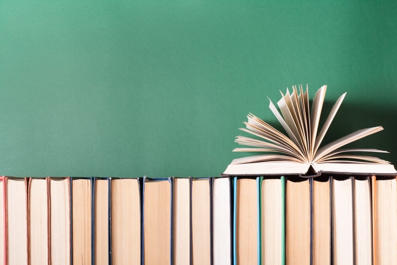 a stack of books sitting on top of a green chalkboard