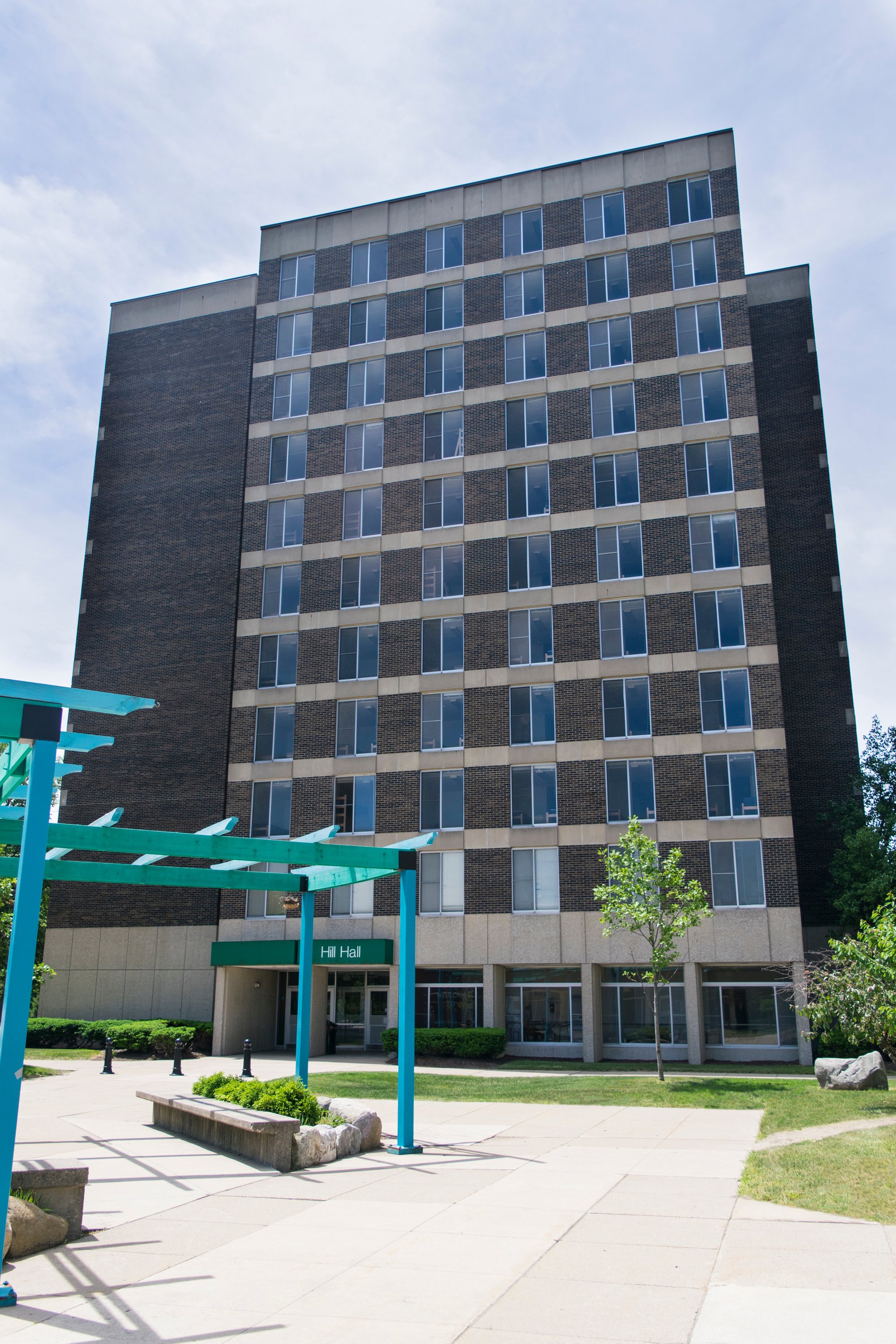 a large brick building with a green arbor in front of it